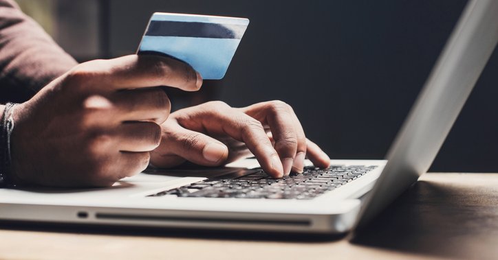 Someone types on a laptop while holding a credit card.