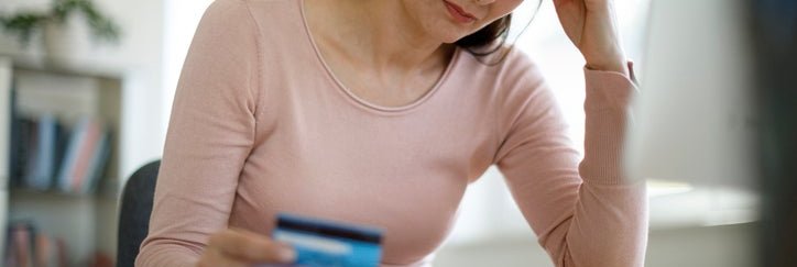 A woman with a credit card, looking worried.