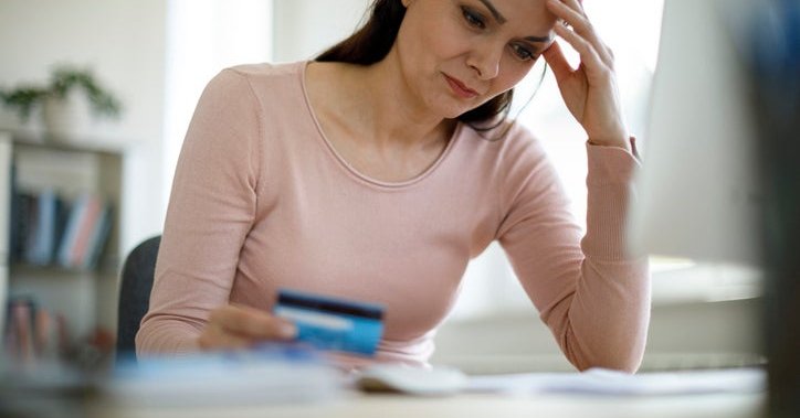 A woman with a credit card, looking worried.