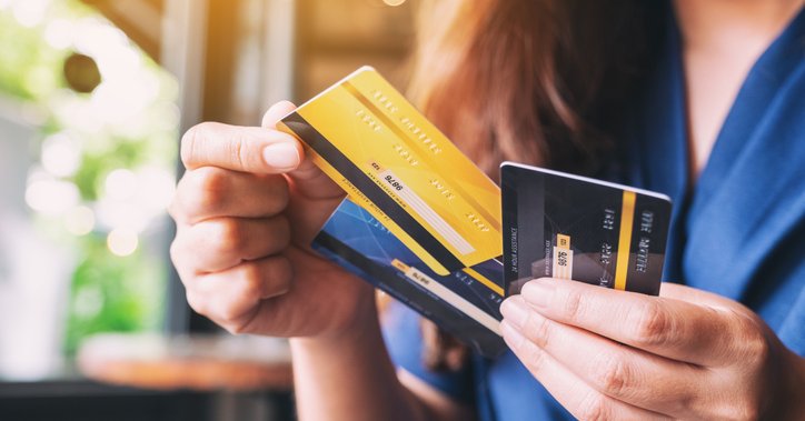 A woman holds three credit cards.