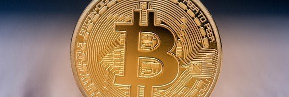 A physical gold coin marked with the bitcoin B.