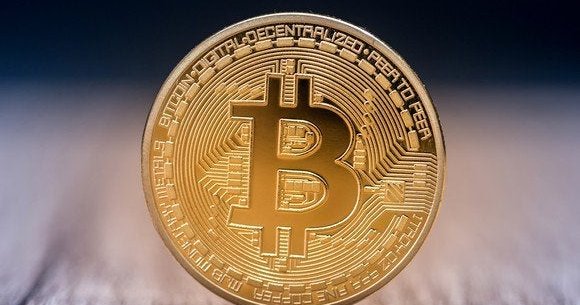 A physical gold coin marked with the bitcoin B.