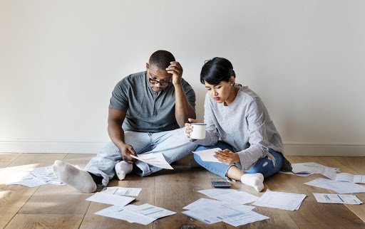 couple sitting on the floor looking over pile of papers