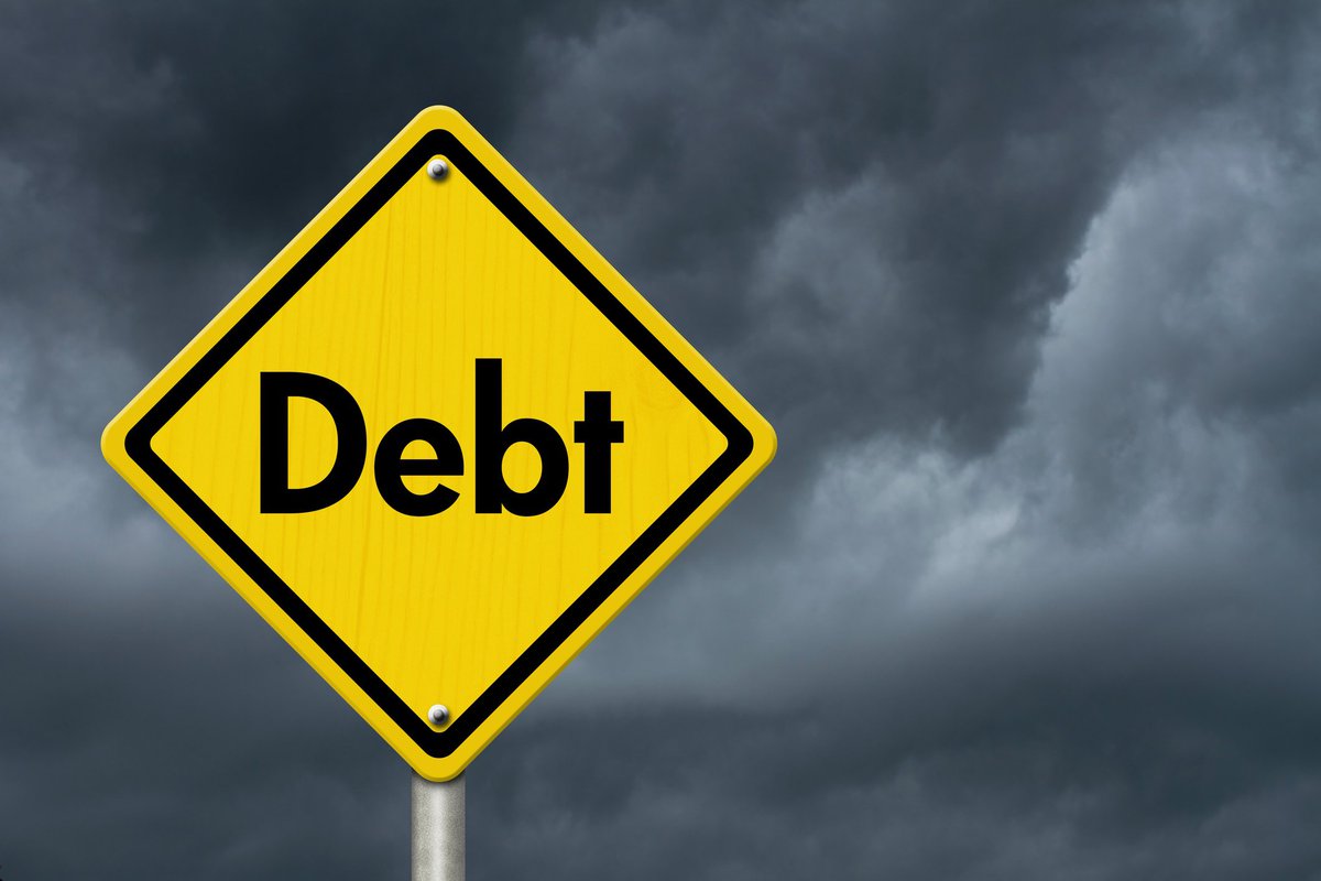 Yellow road sign in shape of diamond with the word debt