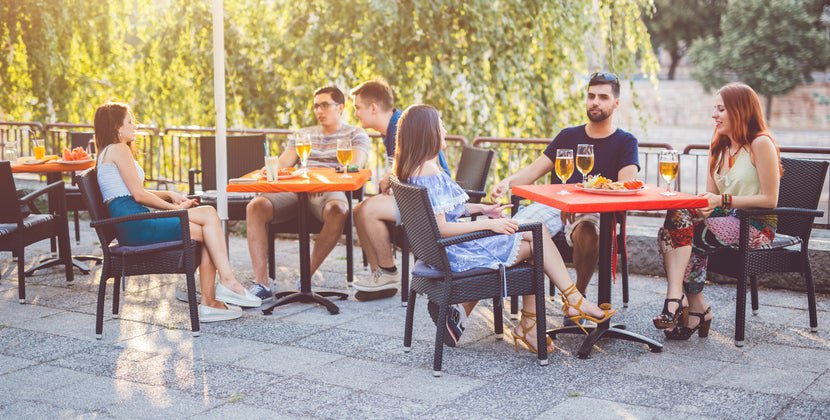 Groups of restaurant customers dining at tables on a sunny patio.