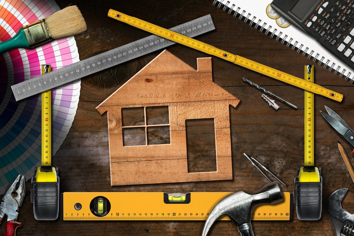 Wooden cutout of house surrounded by home improvement tools.
