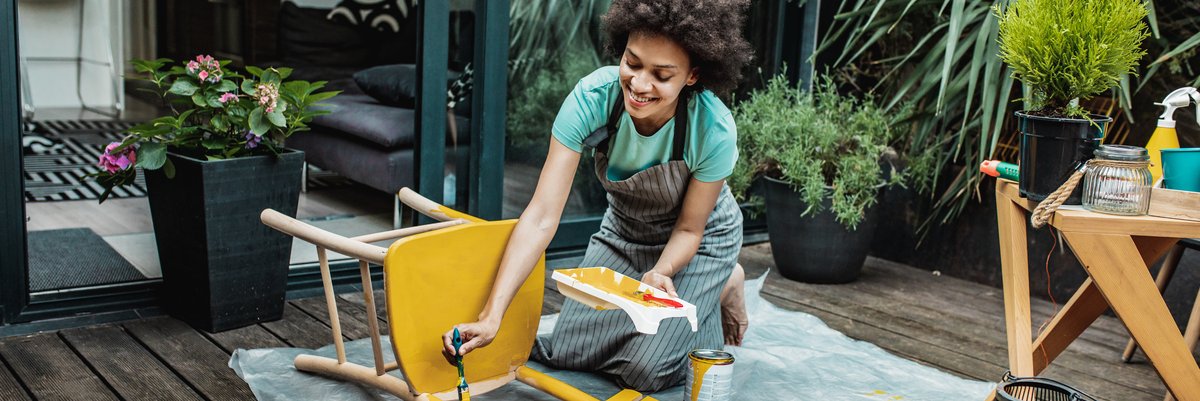 Person giving a wooden chair a fresh coat of paint.