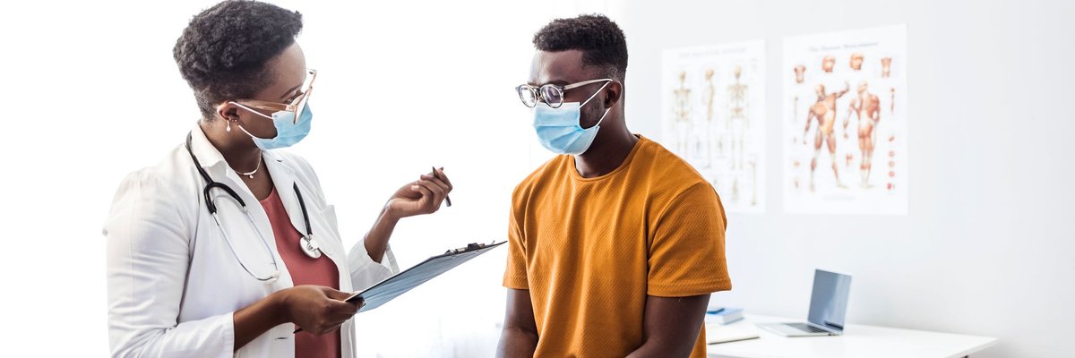 A patient sitting on the table in an exam room and speaking with the doctor.
