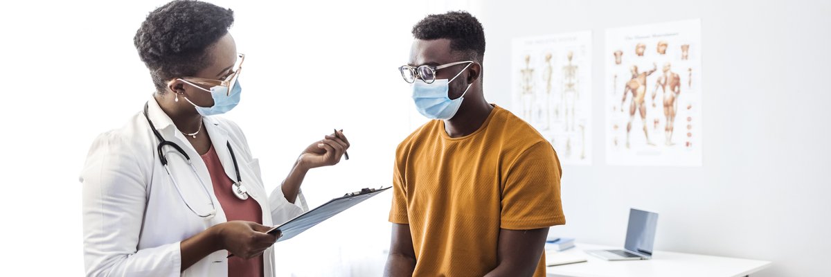 A patient sitting on the table in an exam room and speaking with the doctor.