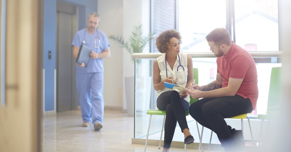 A doctor sitting in the waiting room with her patient and explaining a bill.