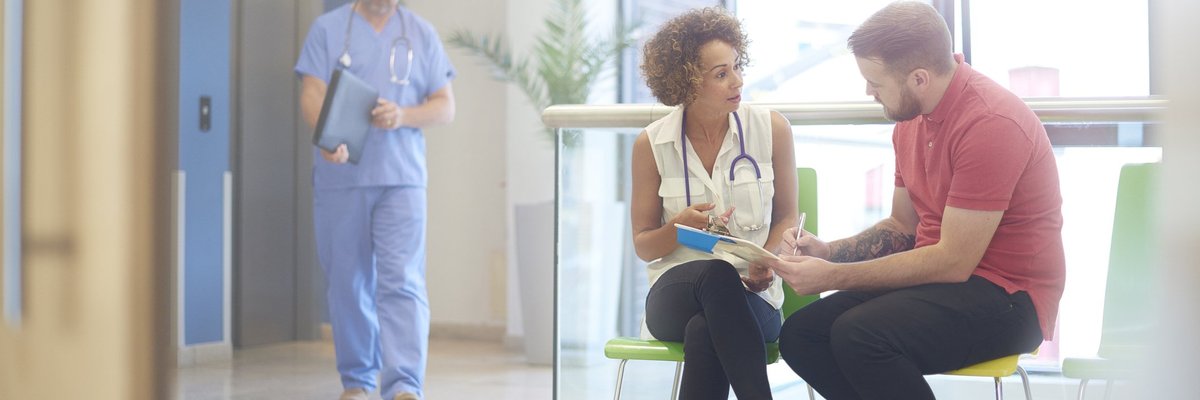 A doctor sitting in the waiting room with her patient and explaining a bill.