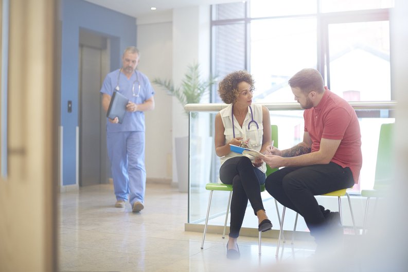 A doctor sitting in the waiting room with her patient and explaining a bill.