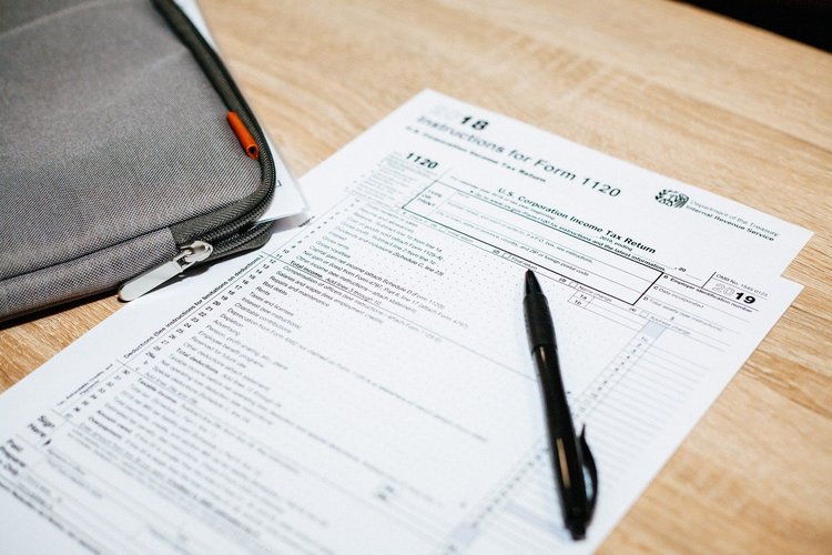 A blank corporate tax return form sits on a wooden desk.