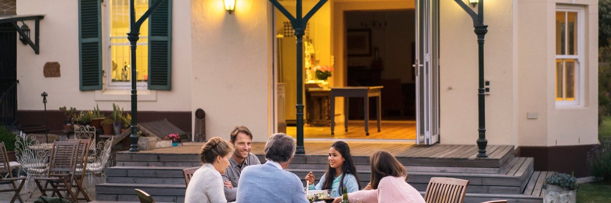 A family of five eating dinner at a backyard patio table.