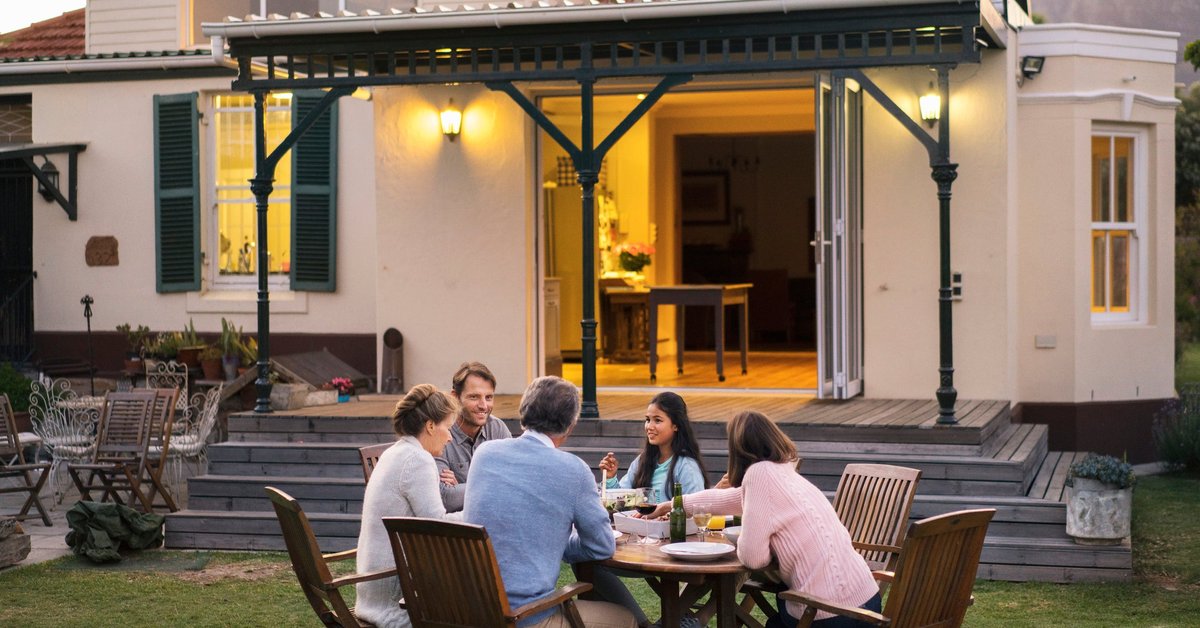 A family of five eating dinner at a backyard patio table.
