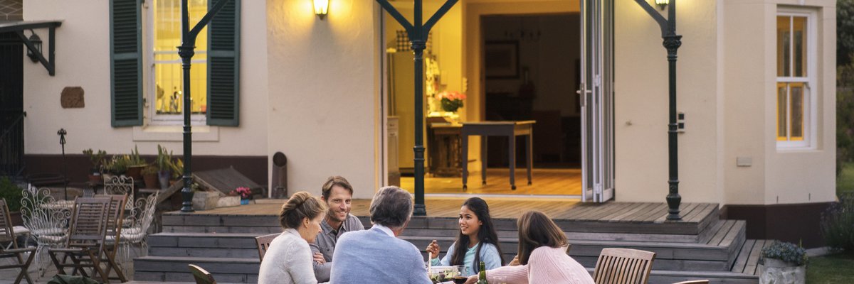 A family of five eating dinner at a backyard patio table.