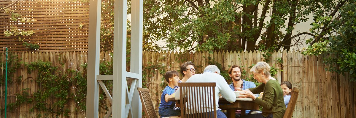 A family eating a meal at a patio table on their back deck.