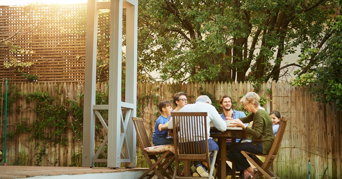 A family eating a meal at a patio table on their back deck.