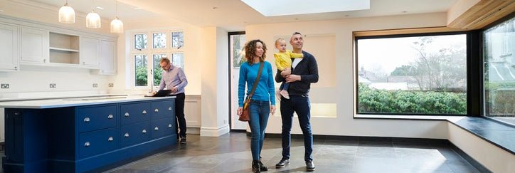 A family looking at the interior of a house with a real estate agent in the background.