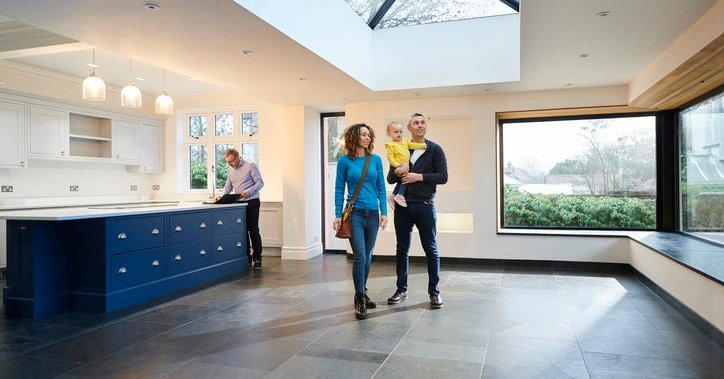 A family looking at the interior of a house with a real estate agent in the background.