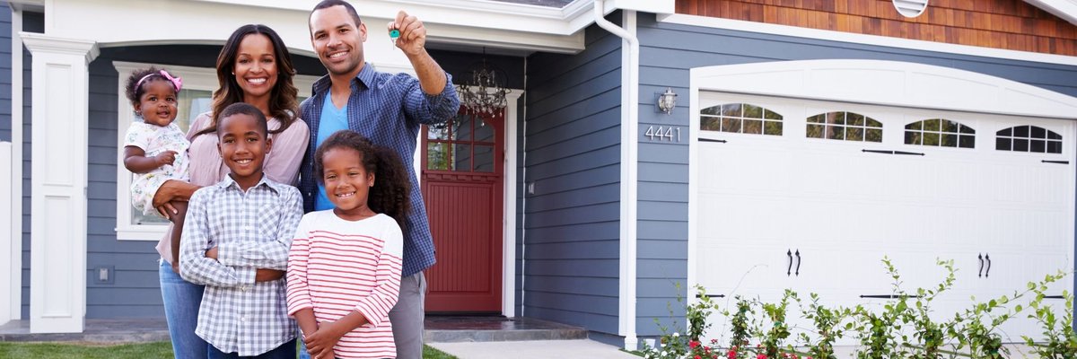 family of five standing in front of home with dad holding up keys