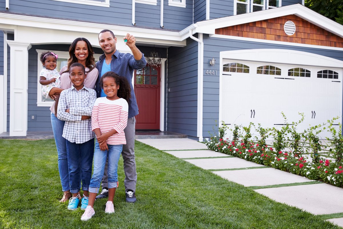 family of five standing in front of home with dad holding up keys