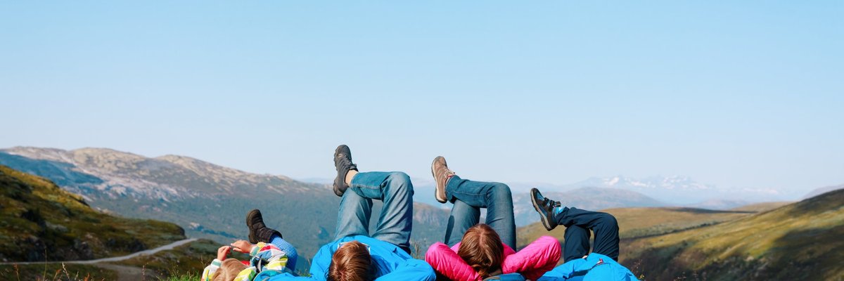 family of four lying on a grassy hill in Norway.