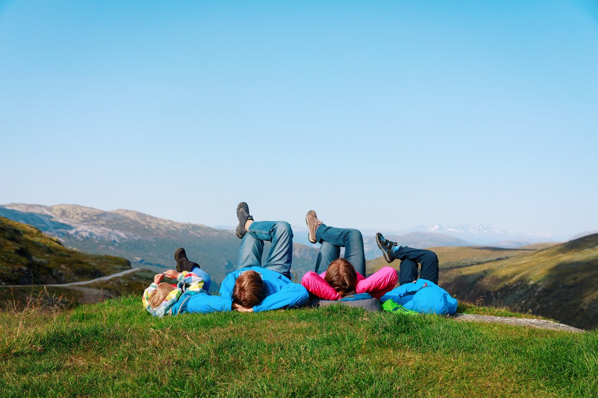 family of four lying on a grassy hill in Norway.