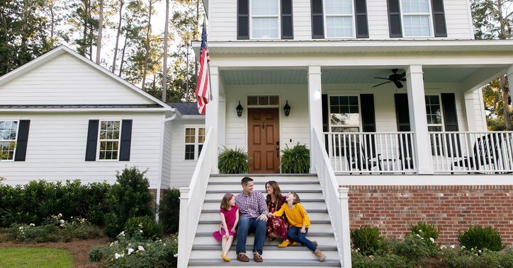 A couple with two kids on the front steps of a house.