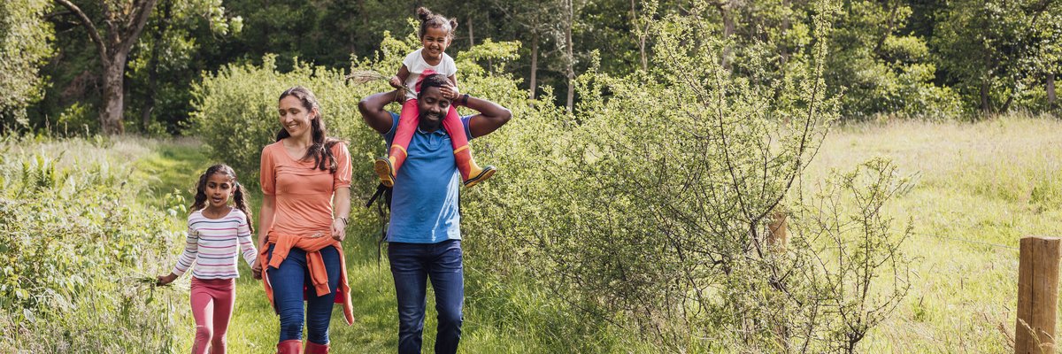 A happy family of four walking along a trail in the woods.