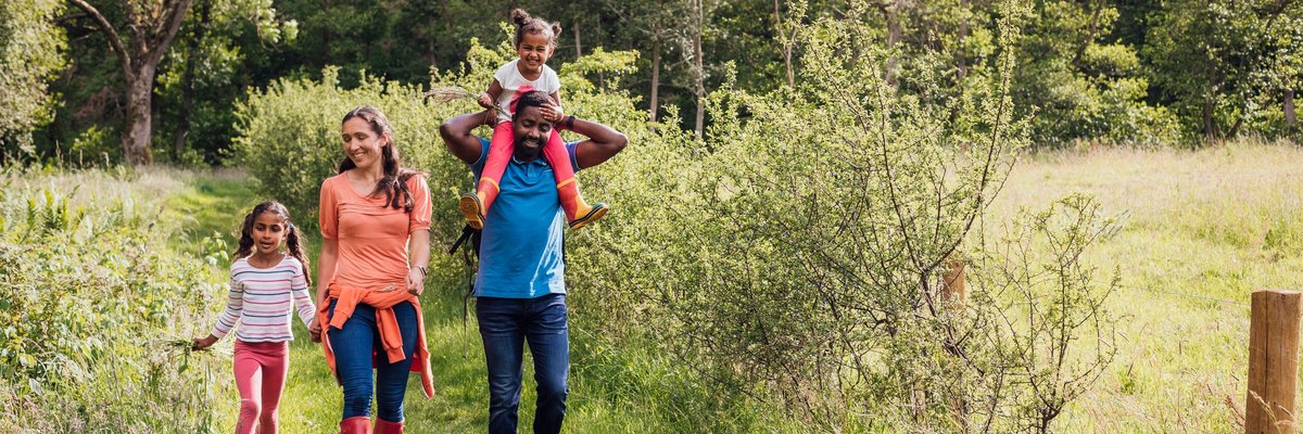 A happy family of four walking along a trail in the woods.