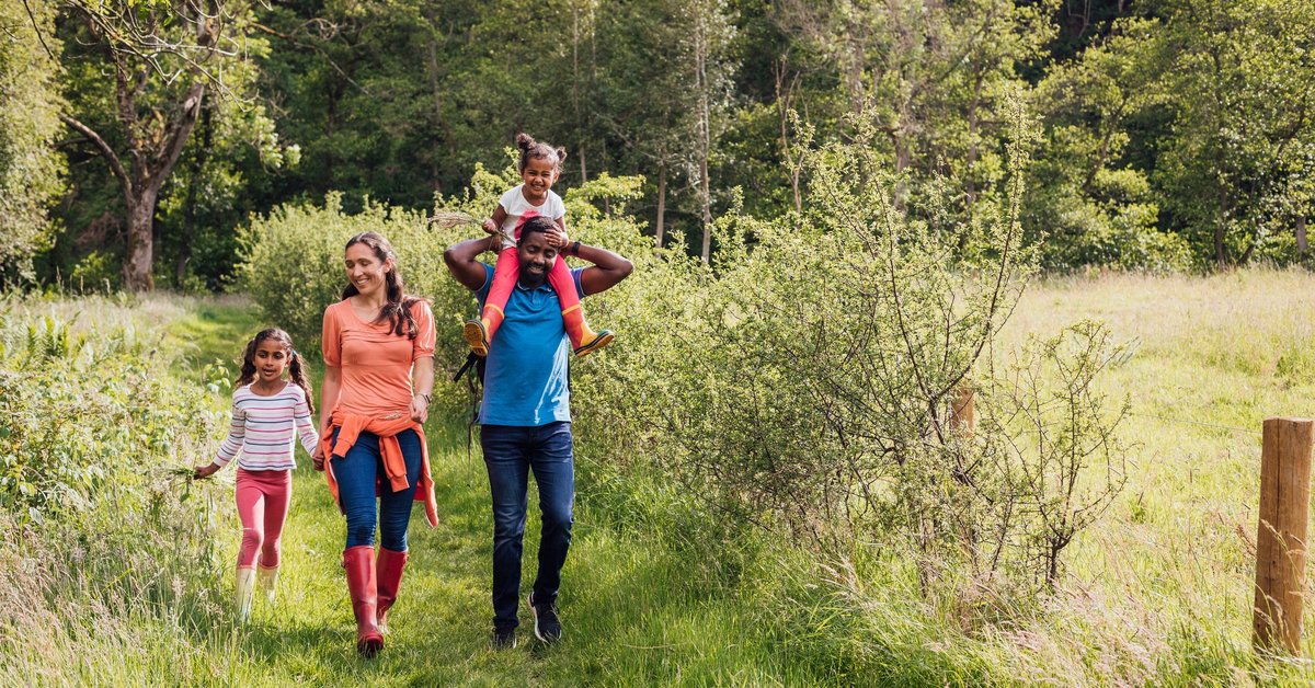 A happy family of four walking along a trail in the woods.