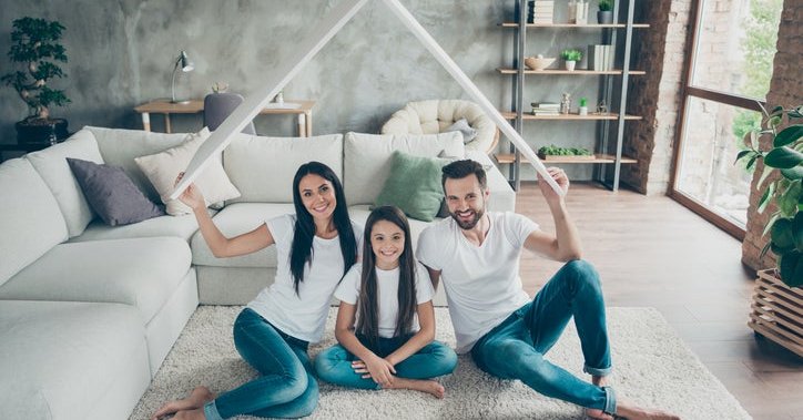 A couple with a young daughter holds up a cardboard roof.