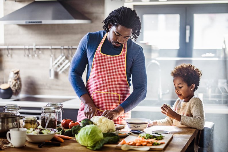A father and young daughter cooking a meal together in the kitchen.