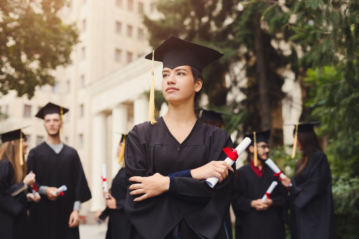 A female college graduate holding her diploma and looking serious.