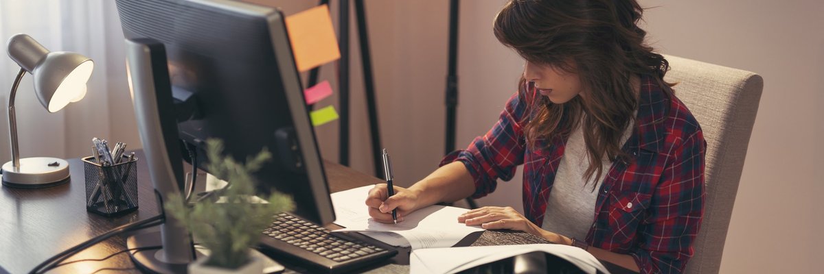 Woman taking notes at desk.