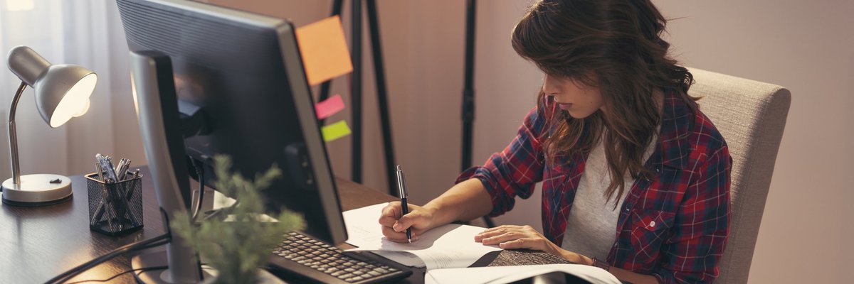 Woman taking notes at desk.