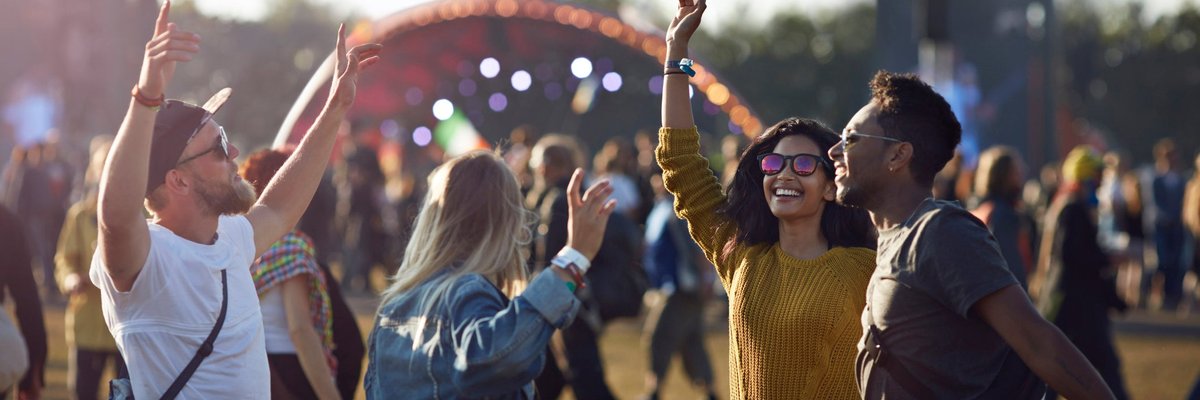 A group of friends dancing in the crowd as they walk to the stage at a music festival.