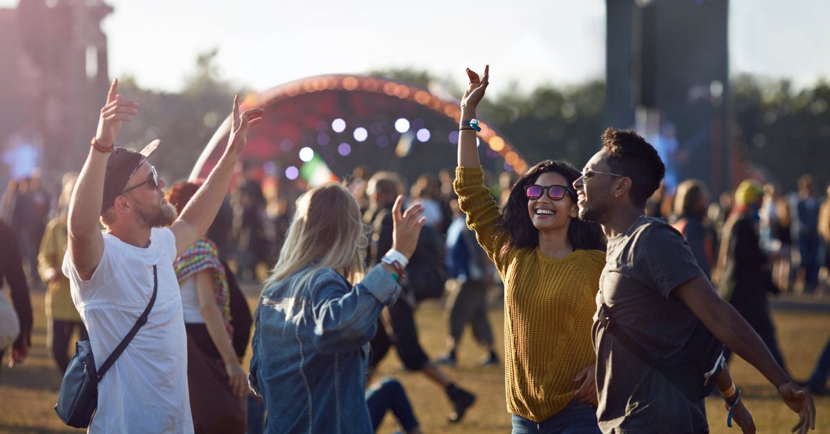 A group of friends dancing in the crowd as they walk to the stage at a music festival.