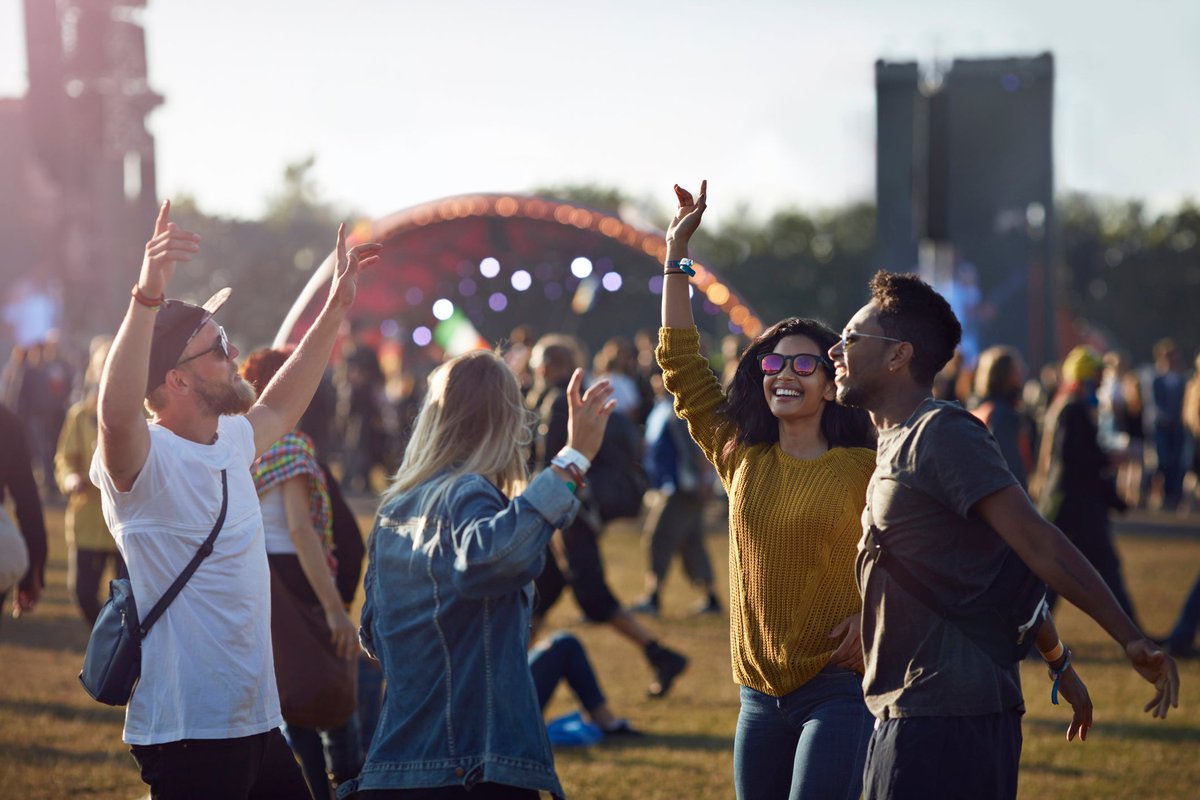 A group of friends dancing in the crowd as they walk to the stage at a music festival.