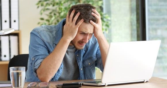 man looking at computer frustrated and confused