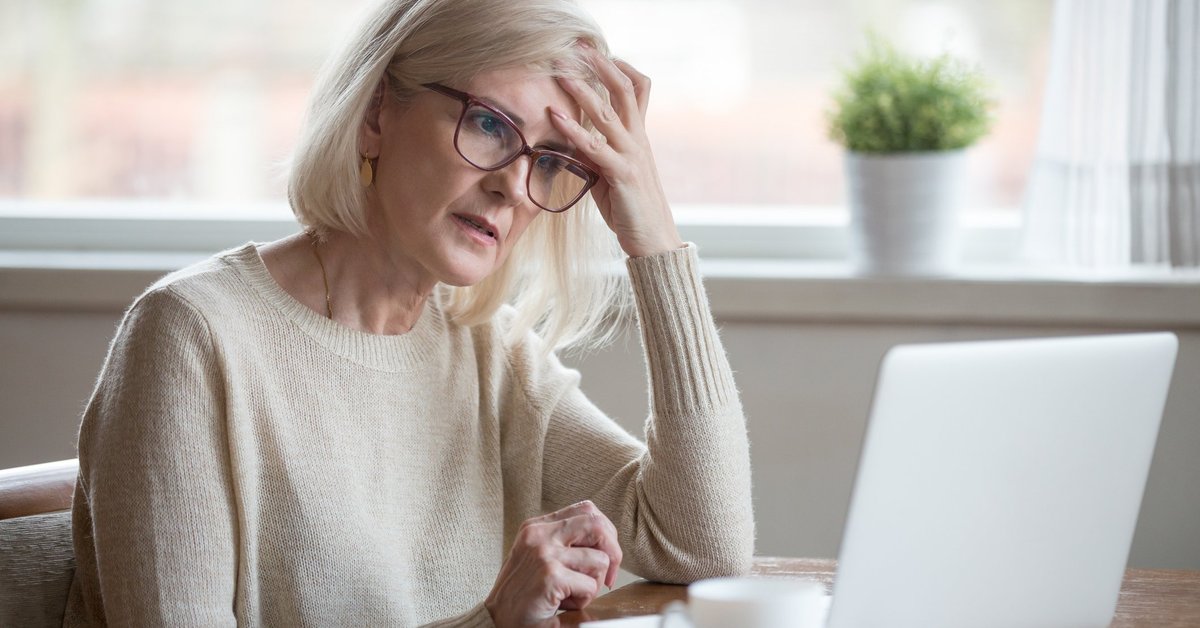Senior woman looking at laptop with frustrated expression