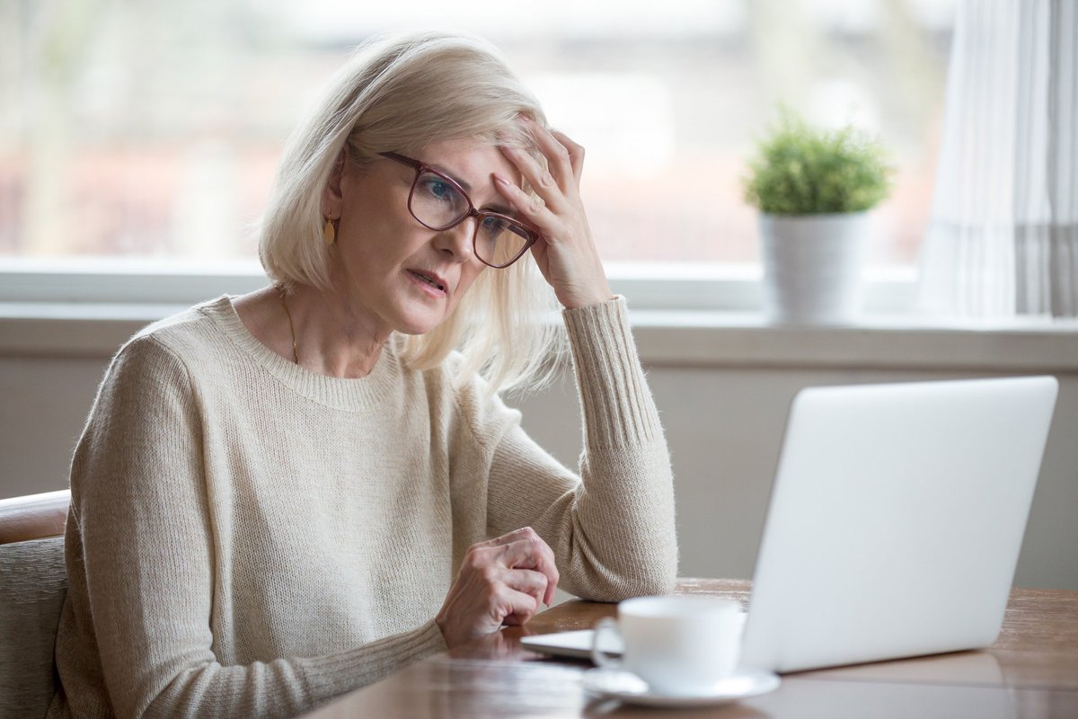 Senior woman looking at laptop with frustrated expression