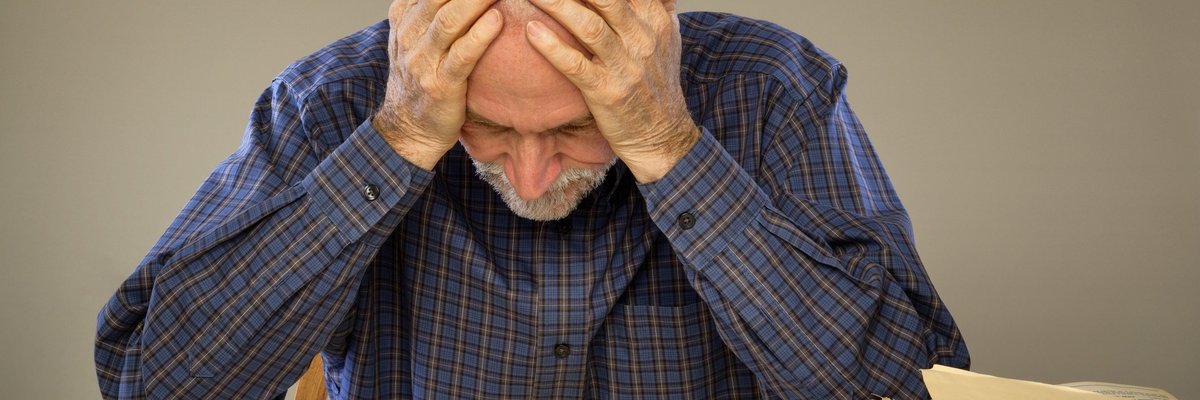 Frustrated man looking at bills on a desk.