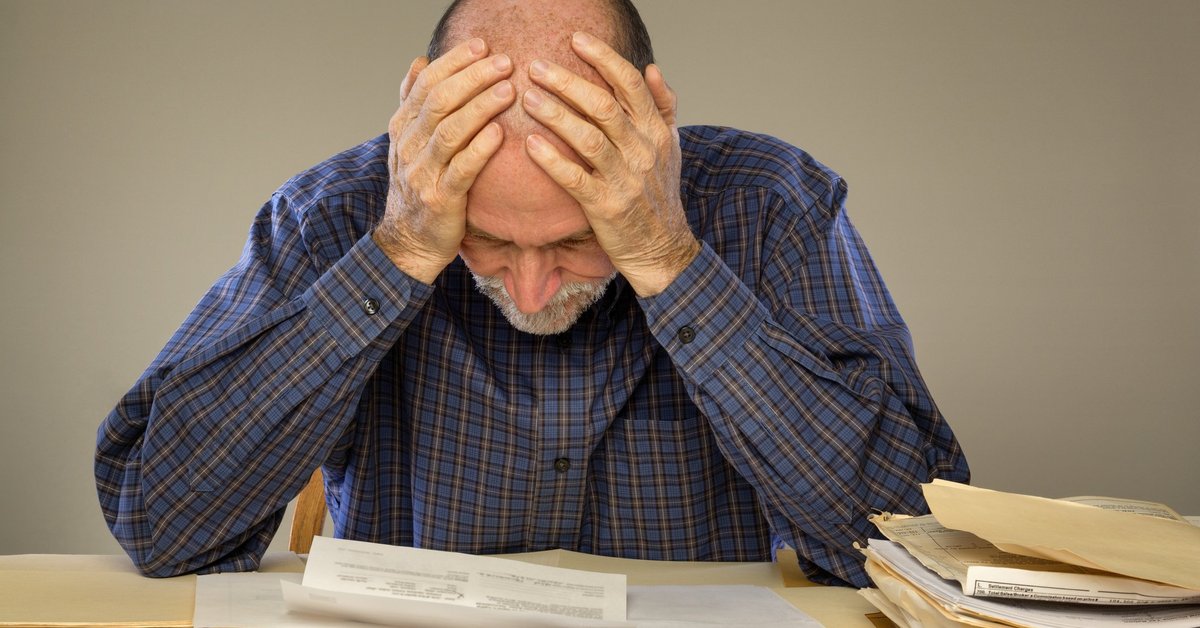 Frustrated man looking at bills on a desk.