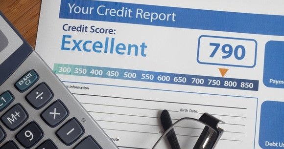 A paper copy of a credit report, under a calculator and a pair of glasses.