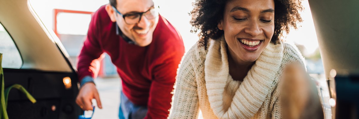 Couple loading grocery bags into vehicle.