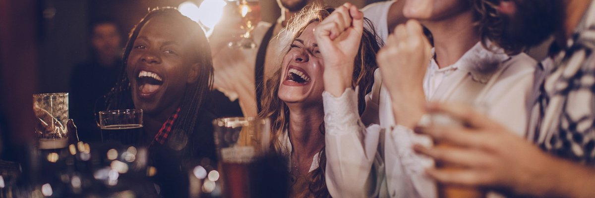 A group of friends laughing over drinks at a bar.