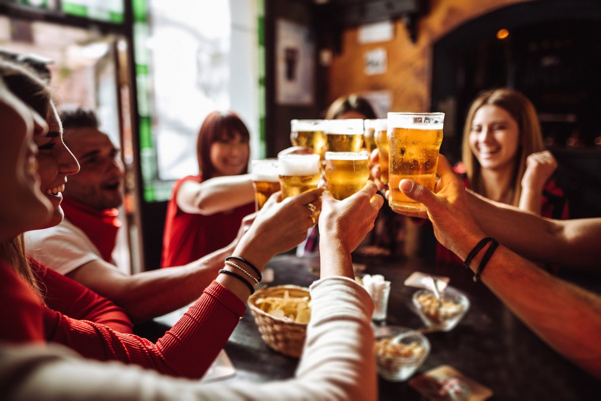 A group of friends cheersing their beers at happy hour.