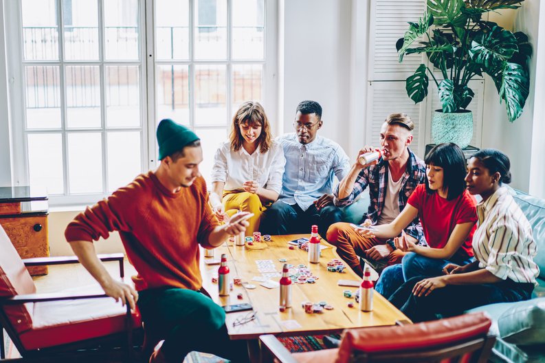 A group of friends sitting around a living room coffee table playing poker.